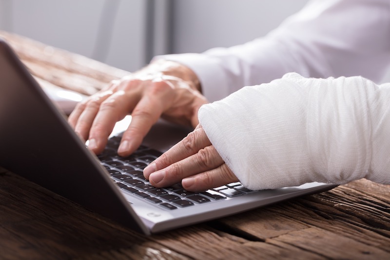 Person With His Hand In A Cast Using A Laptop